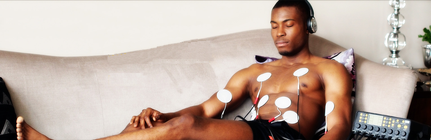 Relaxed man wearing headphones with an electronic muscle stimulator attached to his chest - Tone-A-Matic Electronic Muscle Stimulators in Canada